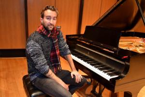 student sits at piano bench wearing a scarf