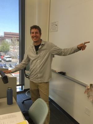 a man pointing towards a white board in a classroom