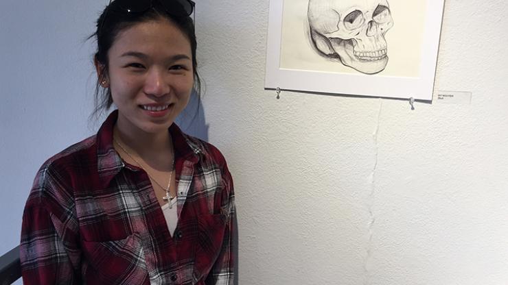 woman standing in front of a drawing of a skull