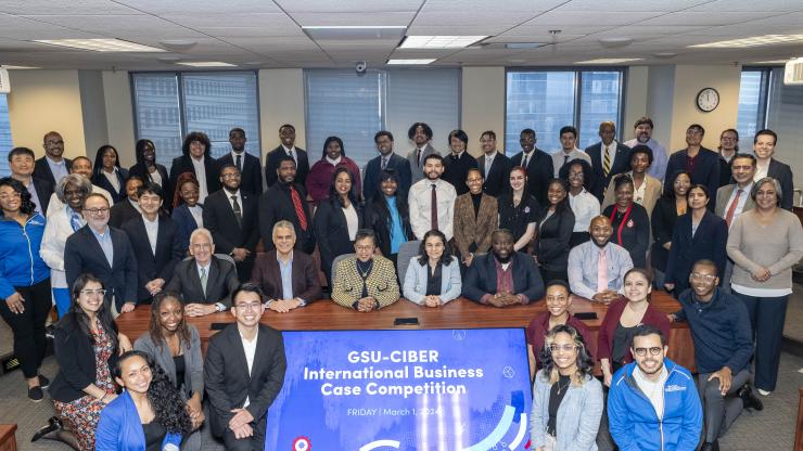 Group of students and scholars posing with a GSU-CIBER sign.