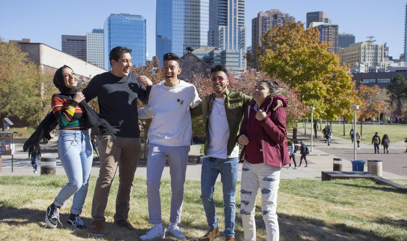 group of 5 students laughing on campus