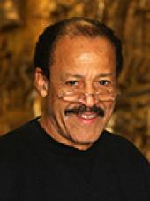 headshot of man in black shirt wearing glasses
