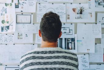 man looking at poster of finances with a white background and in a stripped shirt
