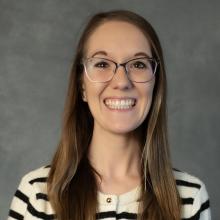 Woman with long brown hair wearing glasses and striped top