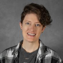 Woman with wavy short brown hair wearing plaid shirt