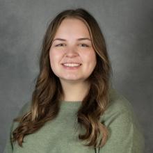 Woman with long brown hair wearing a green top