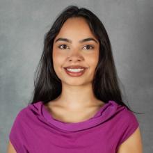 Woman with long dark hair wearing a bright pink top