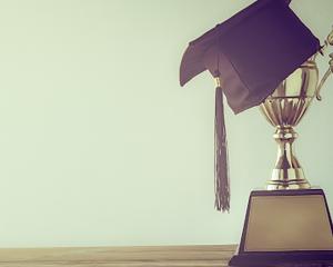 image of trophy with a graduation cap and sunset 