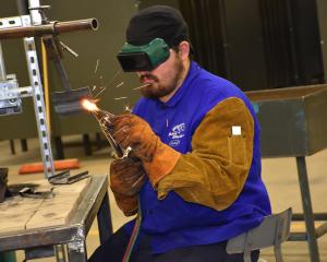 man welding while wearing protective goggles and gloves