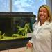 white woman standing in a lab in front of a fish tank smiling