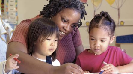 image of female teacher coloring with two pre-school girls