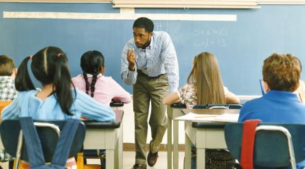 image of male elementary school teacher in front of classroom teaching