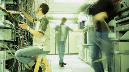 image of three people in a computer server room working on computer cables