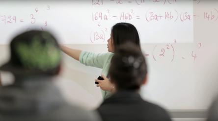 Math teacher at the white board pointing to math equations 