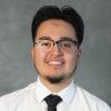 Guy  with short black hair wearing glasses, white shirt and black tie