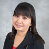 Woman with shoulder length dark hair, bangs wearing black blazer and red top