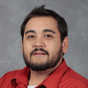 Person with short dark brown hair, beard and mustache wearing red shirt