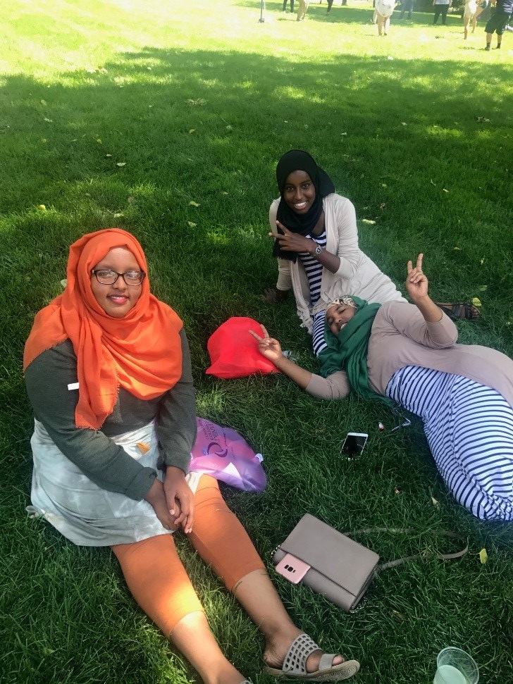 Welcome Back Student to Auraria Campus three famales sitting in grass